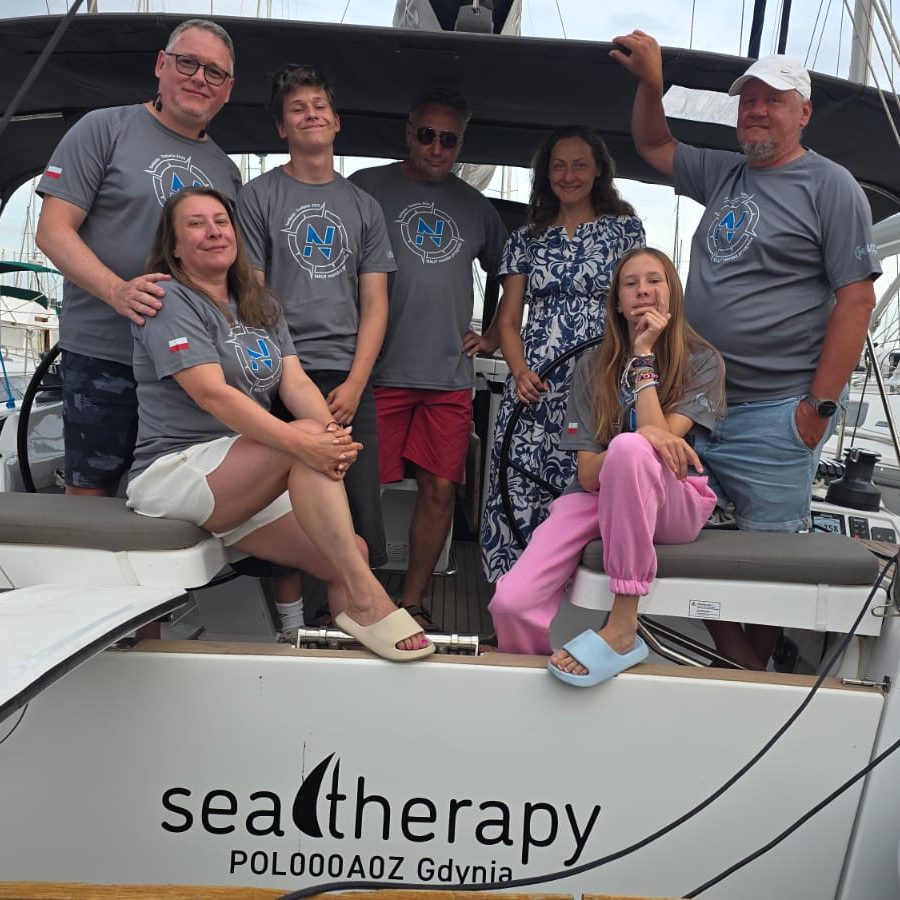 Załoga w szarych koszulkach w kokpicie jachtu Seatherapy
